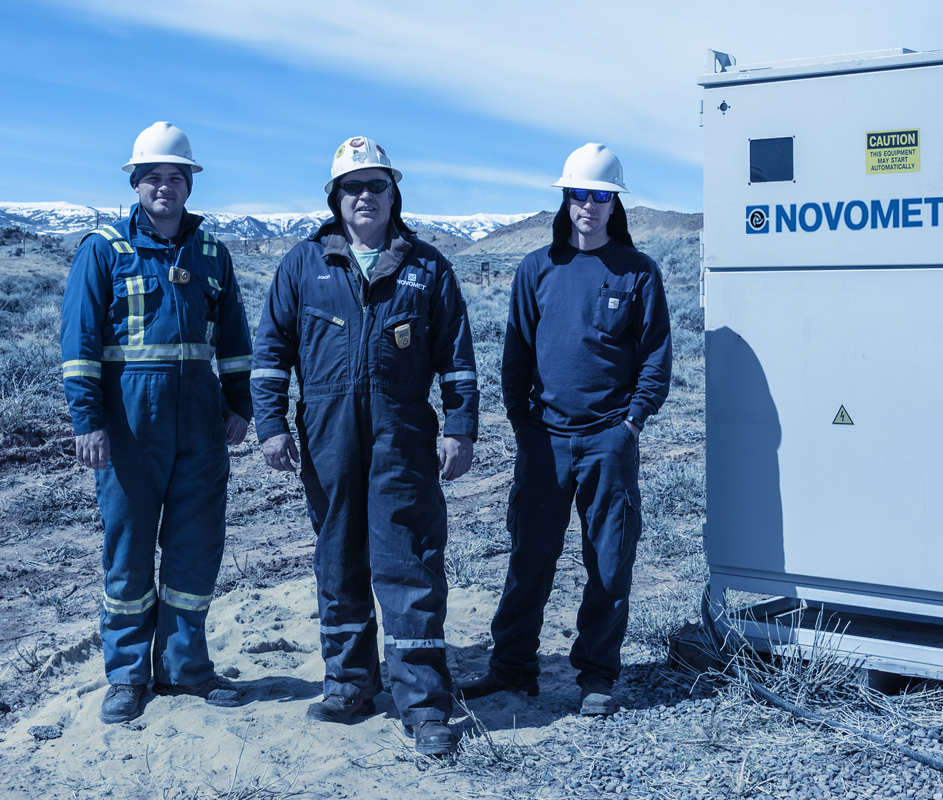 Three workers standing in front of distant snow-capped mountains on a VSD installation